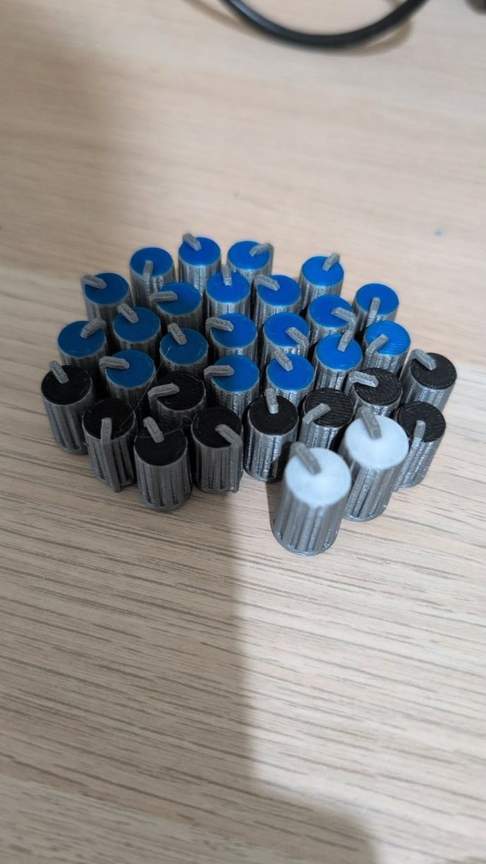A batch of 3D printed amplifier knobs in blue, black, and white